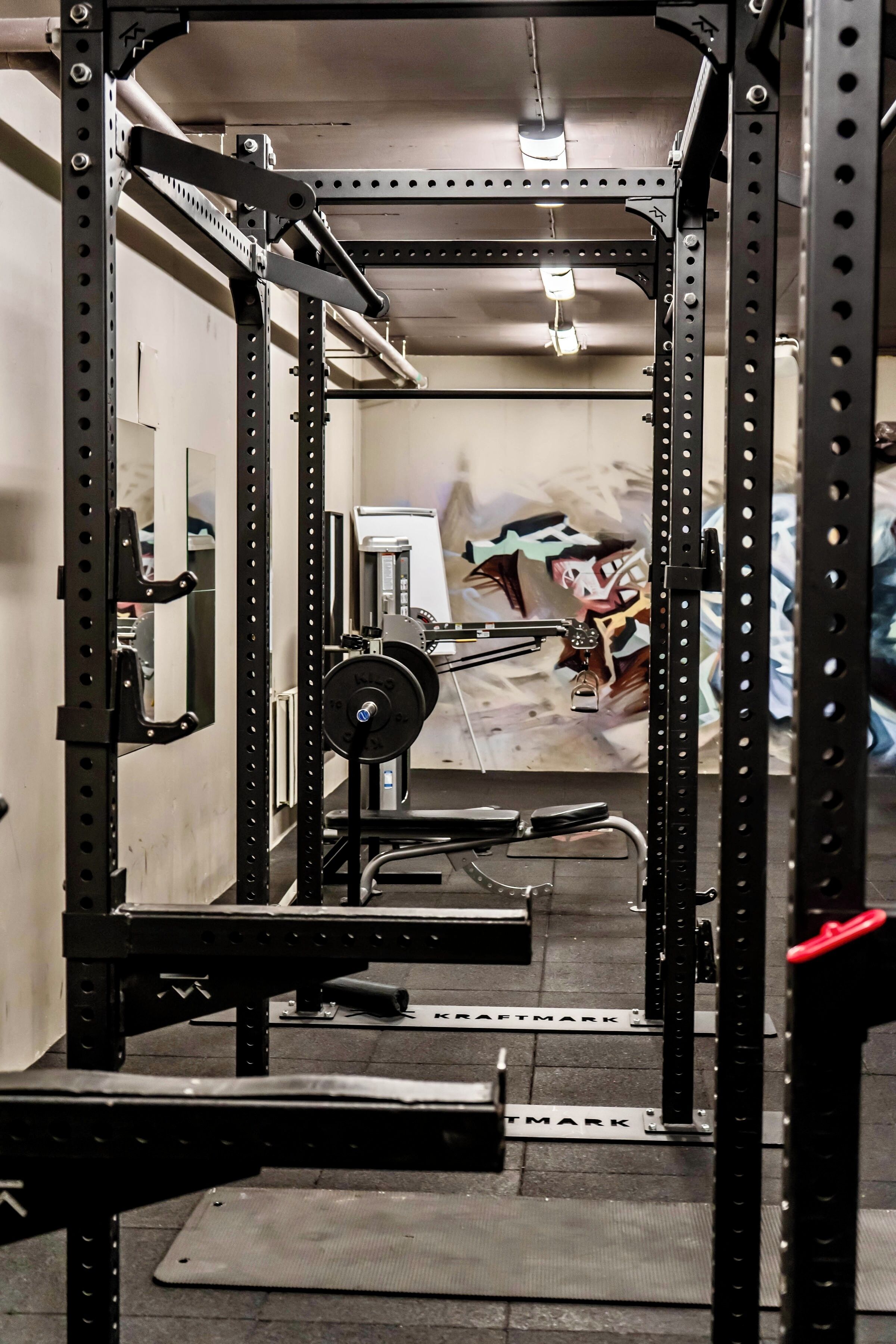 A gym with weightlifting equipment, a bench, and a mirror.