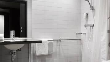 A modern bathroom with a white sink, mirror, and shower.