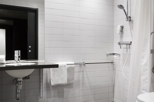 Un baño moderno con lavamanos, espejo y ducha blancos.