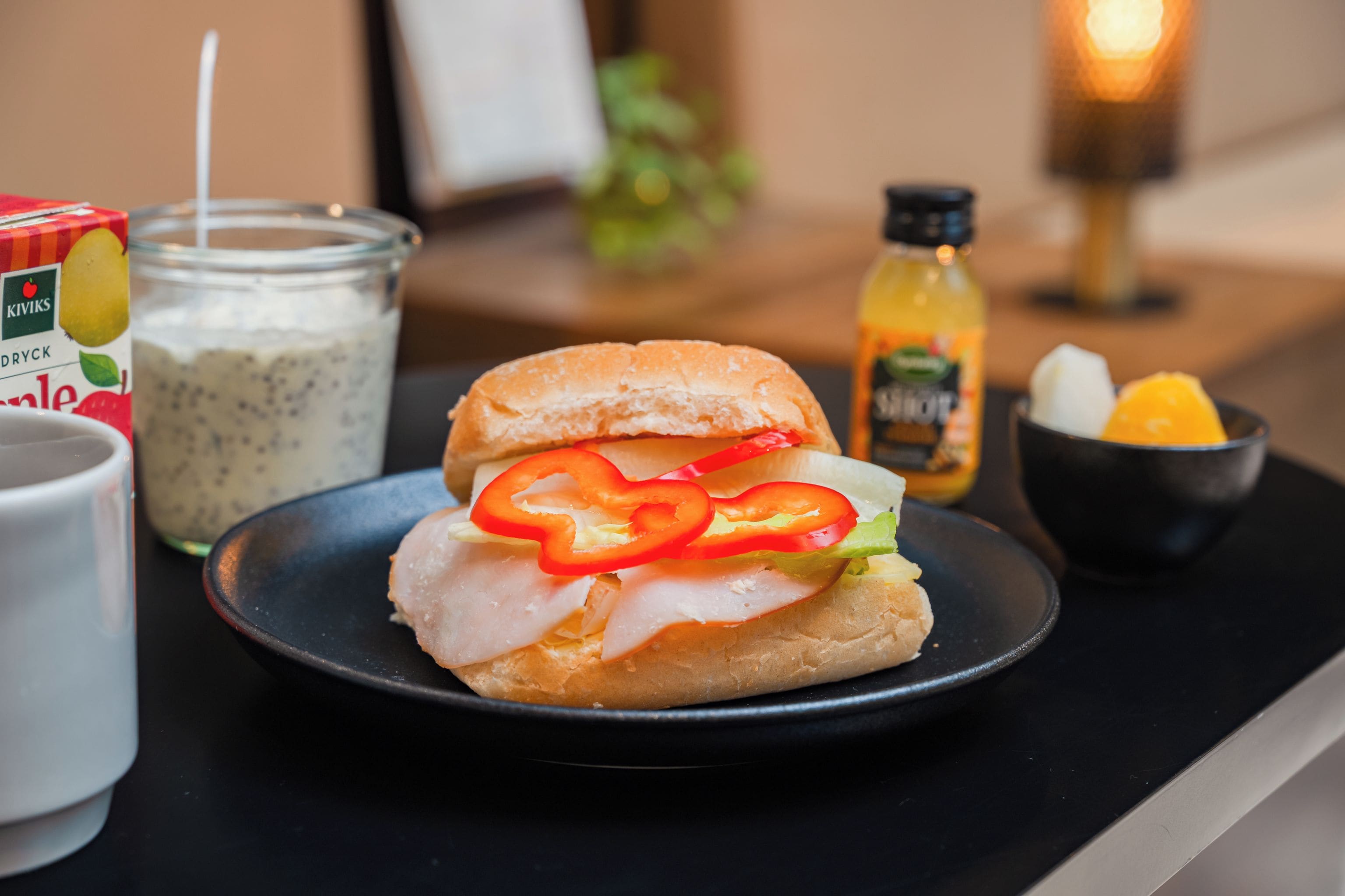 Un sandwich sur une assiette, avec un pot de vinaigrette et une bouteille de sauce en arrière-plan.