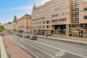 Vista de la calle con un hotel llamado 'Comfort Hotel Xpress' en primer plano, que presenta una fachada moderna con grandes ventanales y un letrero.
