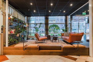 Un interior moderno con una zona de estar, plantas y ventanas amplias.