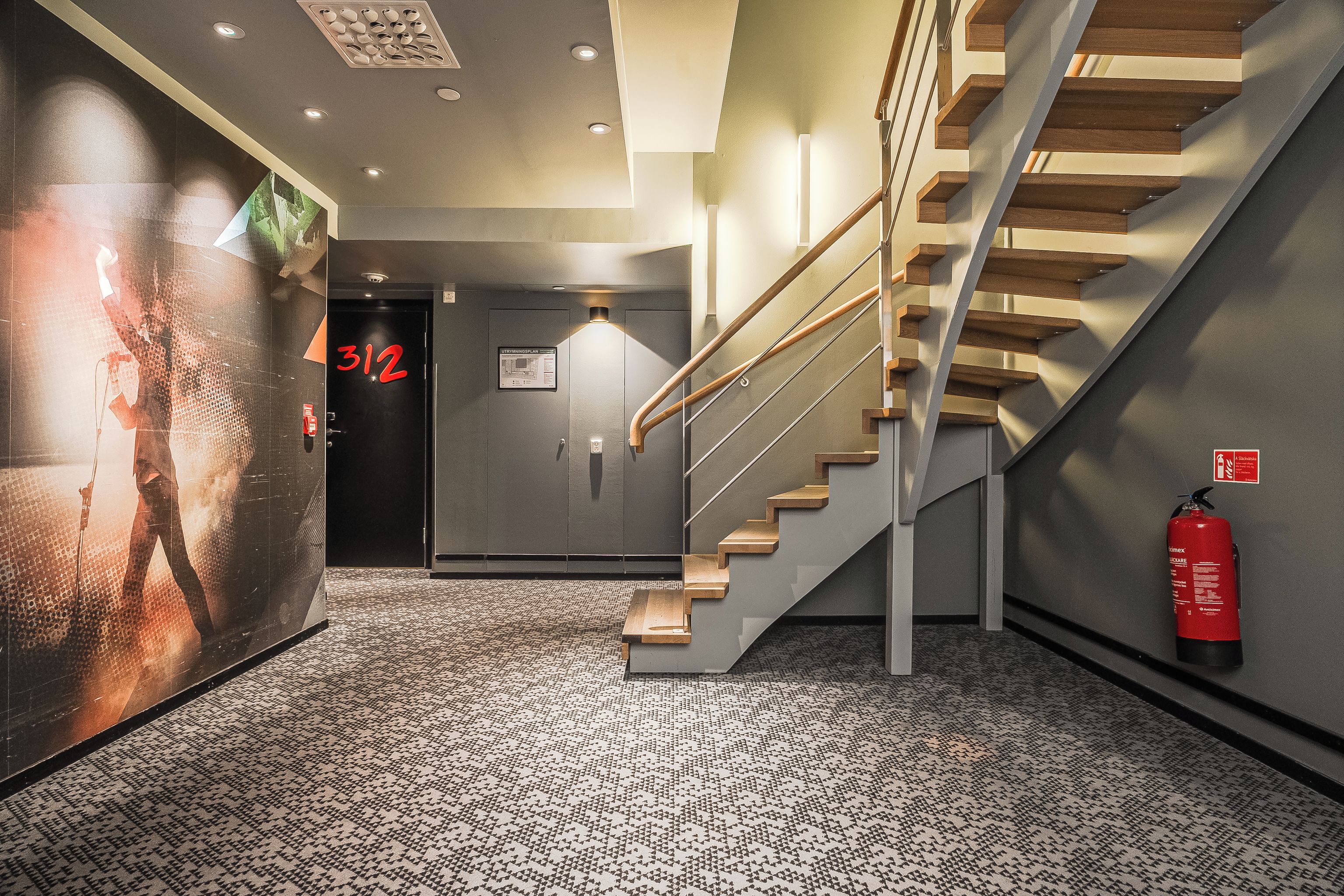 A modern interior with a staircase, a fire extinguisher, and a door marked with the number 312.