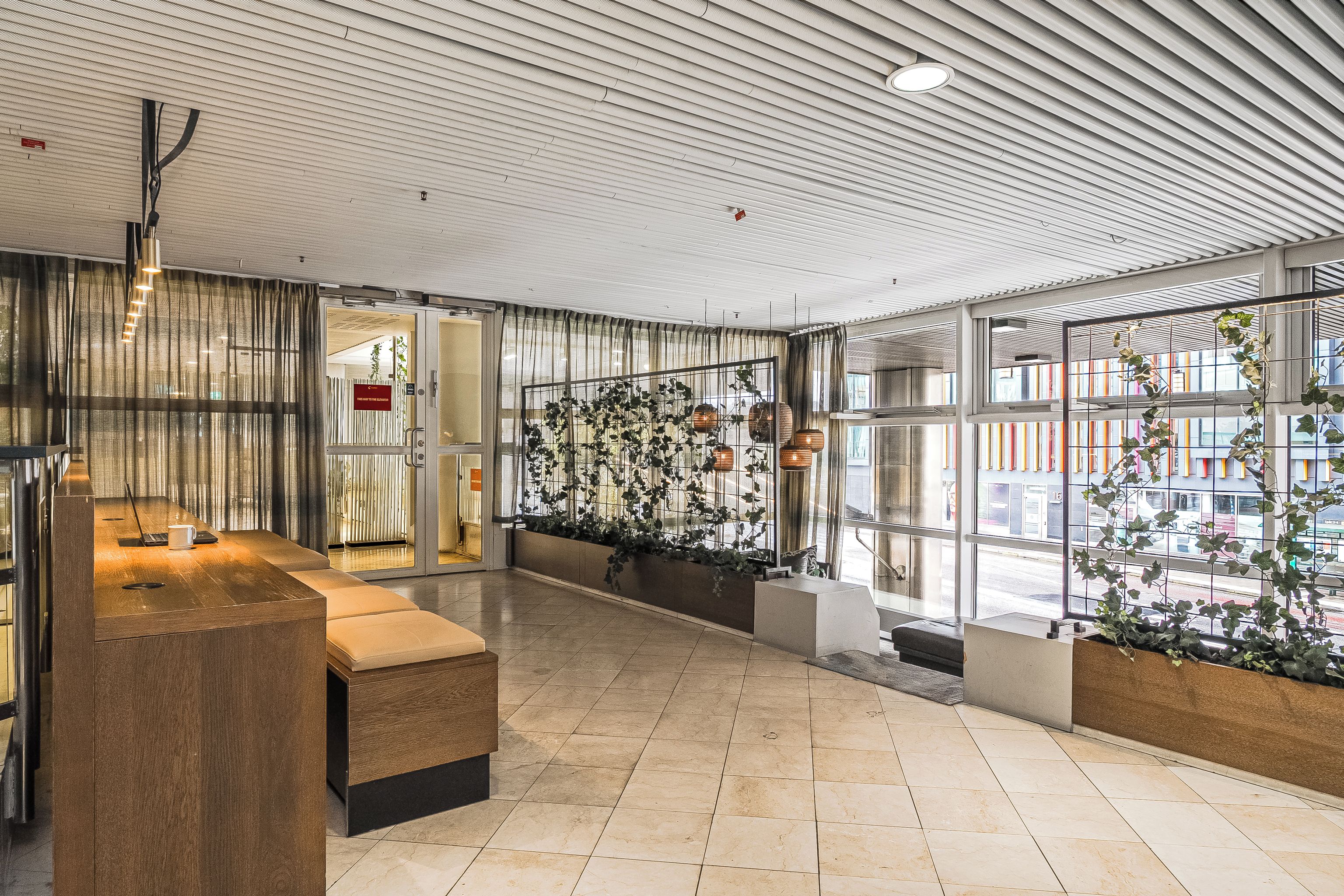 A modern interior with a reception desk, seating area, and large windows.