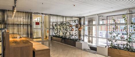 A modern interior with a reception desk, seating area, and large windows.