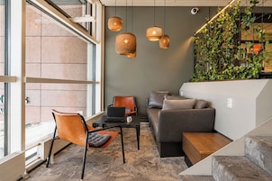 Un intérieur moderne avec un canapé, un fauteuil et un ordinateur portable posé sur une table.