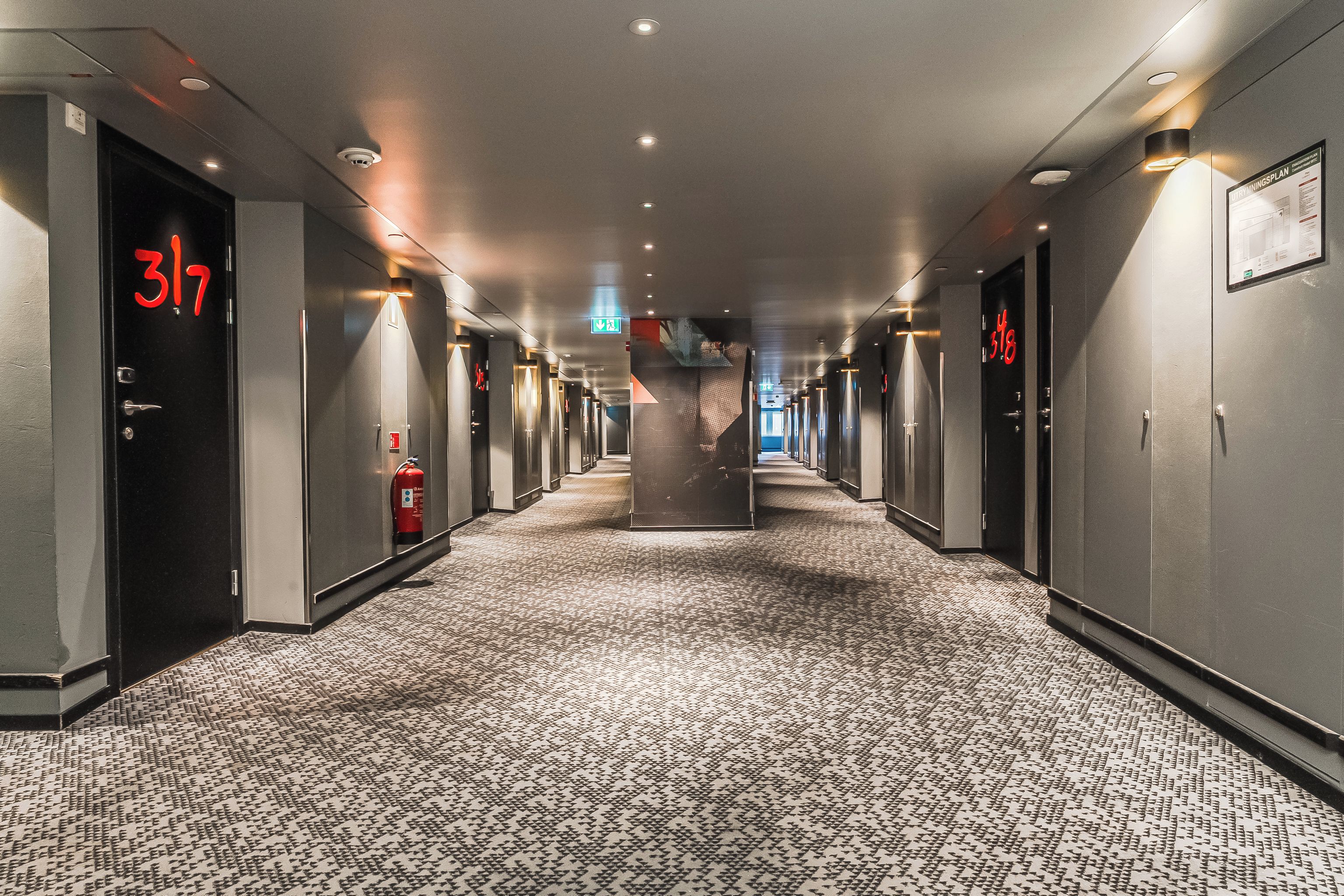 Ein Hotelgang mit mehreren Türen, jede Tür mit einer Nummer gekennzeichnet.