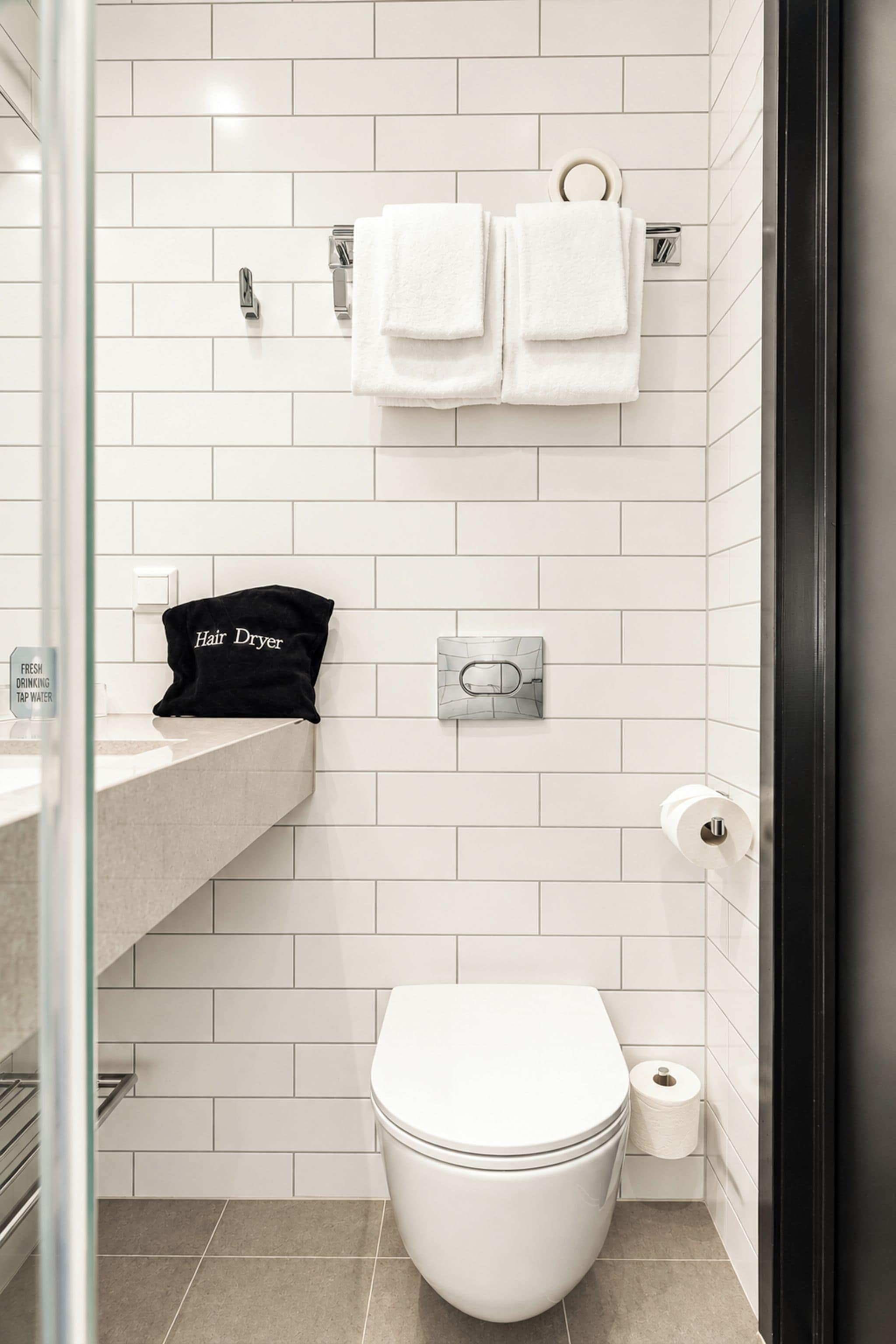 A modern bathroom with a toilet, a hair dryer, and a towel rack.