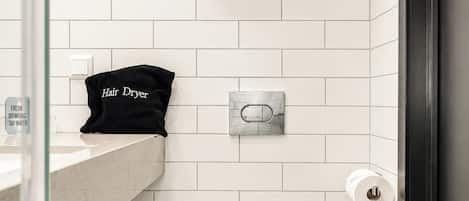 A modern bathroom with a toilet, a hair dryer, and a towel rack.