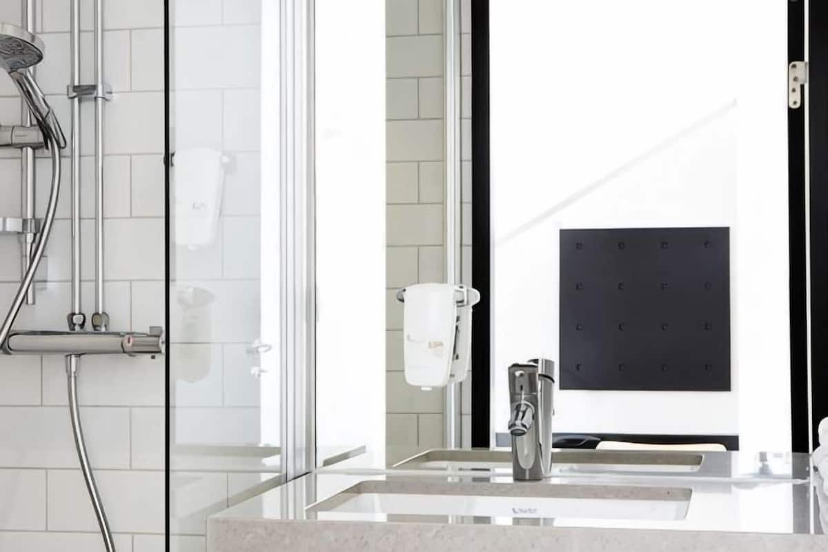 A modern bathroom with a glass shower enclosure, a sink with a mirror, and a towel rack.