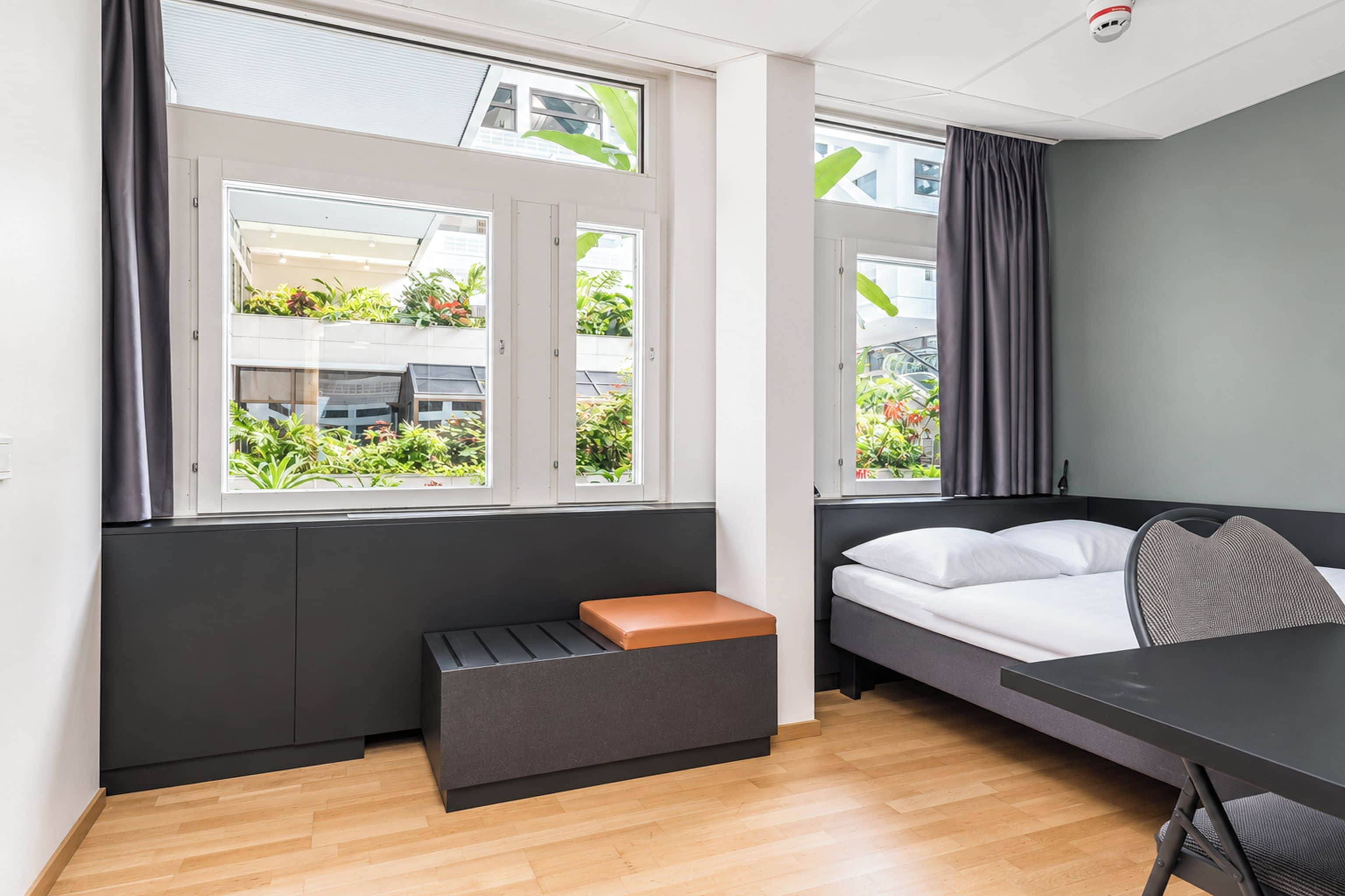 A modern room with a bed, a bench, and a table.