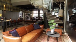 Eine moderne Hotellobby mit einer Ledersofa, einem kleinen Tisch mit Pflanze und einer Treppe.