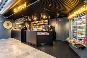 Uma área de recepção moderna com balcão, máquina de café e vitrine refrigerada.