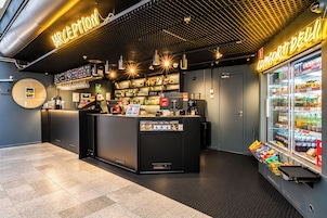 Una moderna zona de recepción con mostrador, máquina de café y vitrina refrigerada.