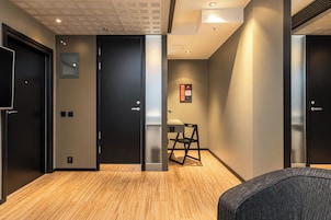 A modern hallway with black doors, a desk with a chair, and a wall-mounted emergency exit sign.