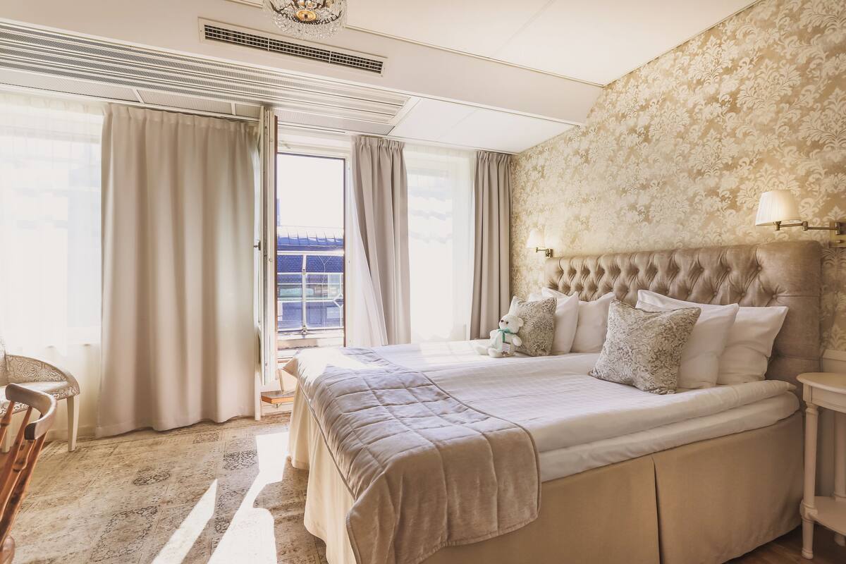 Ein geräumiges Schlafzimmer mit einem großen Bett, Blick auf die Stadt und einem Balkon.
