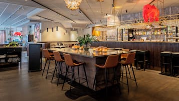 Eine Bar mit einer langen Theke, mehreren Hockern und einer Auswahl an Flaschen und Gläsern.