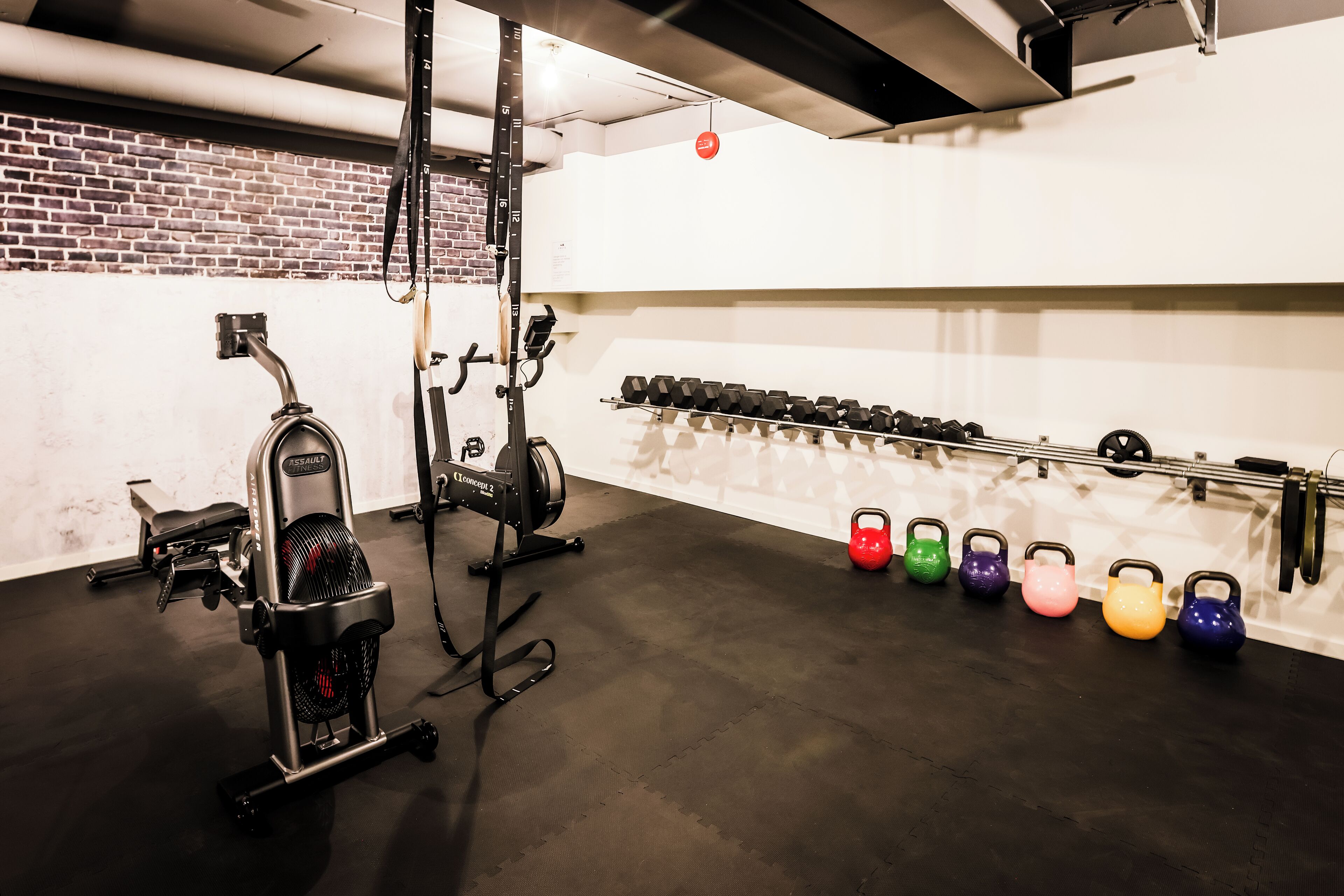 A gym with exercise equipment, including a stationary bike, dumbbells, and kettlebells.