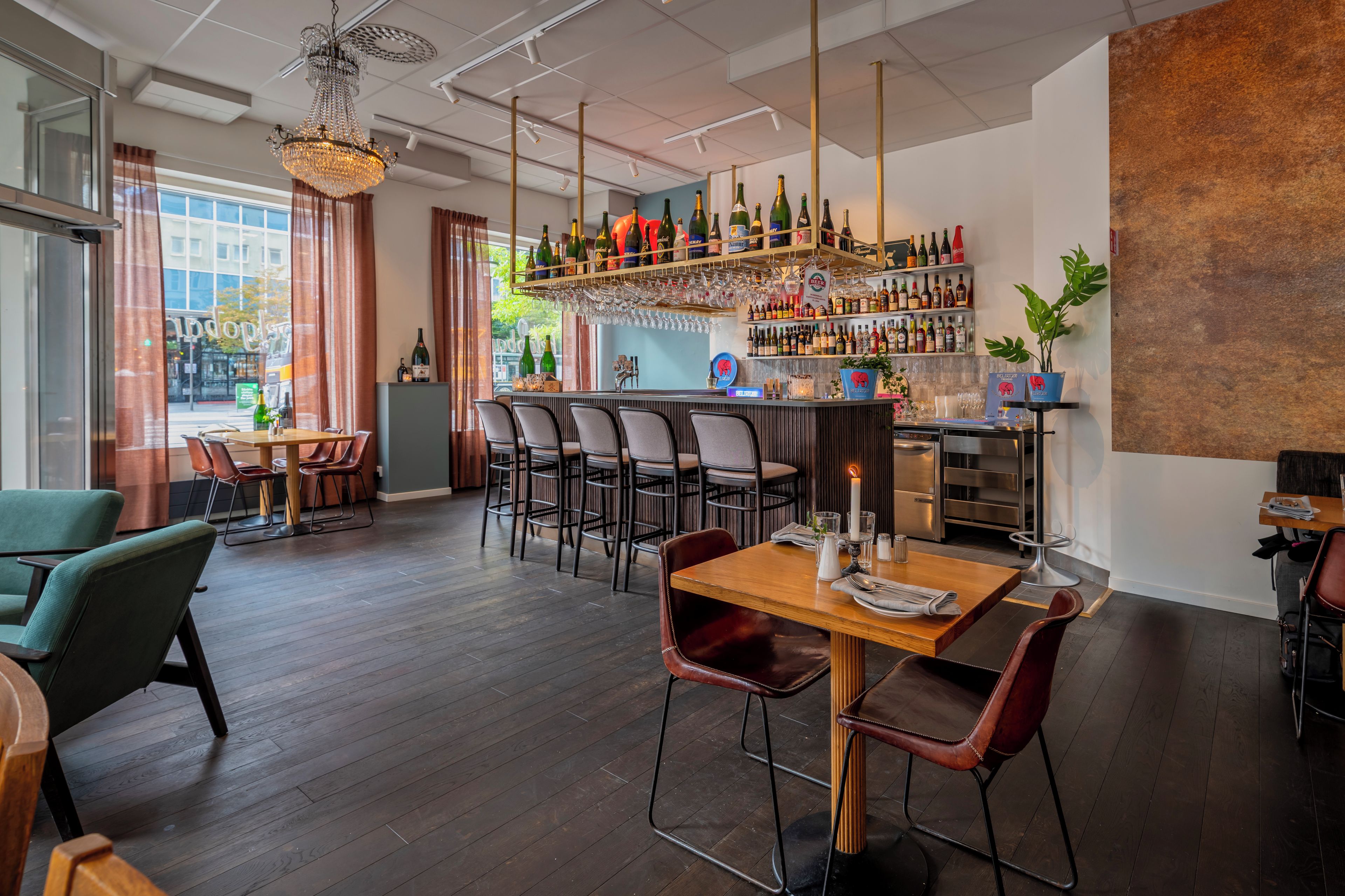 A bar area with a variety of bottles and glasses, wooden furniture, and a large window.