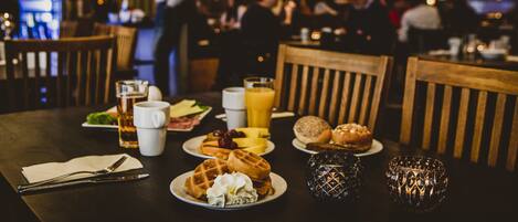 A restaurant setting with a table set for breakfast, including waffles, eggs, and juice.