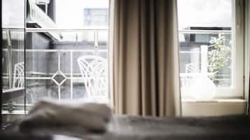 A room with a view of the city through a window with a curtain.