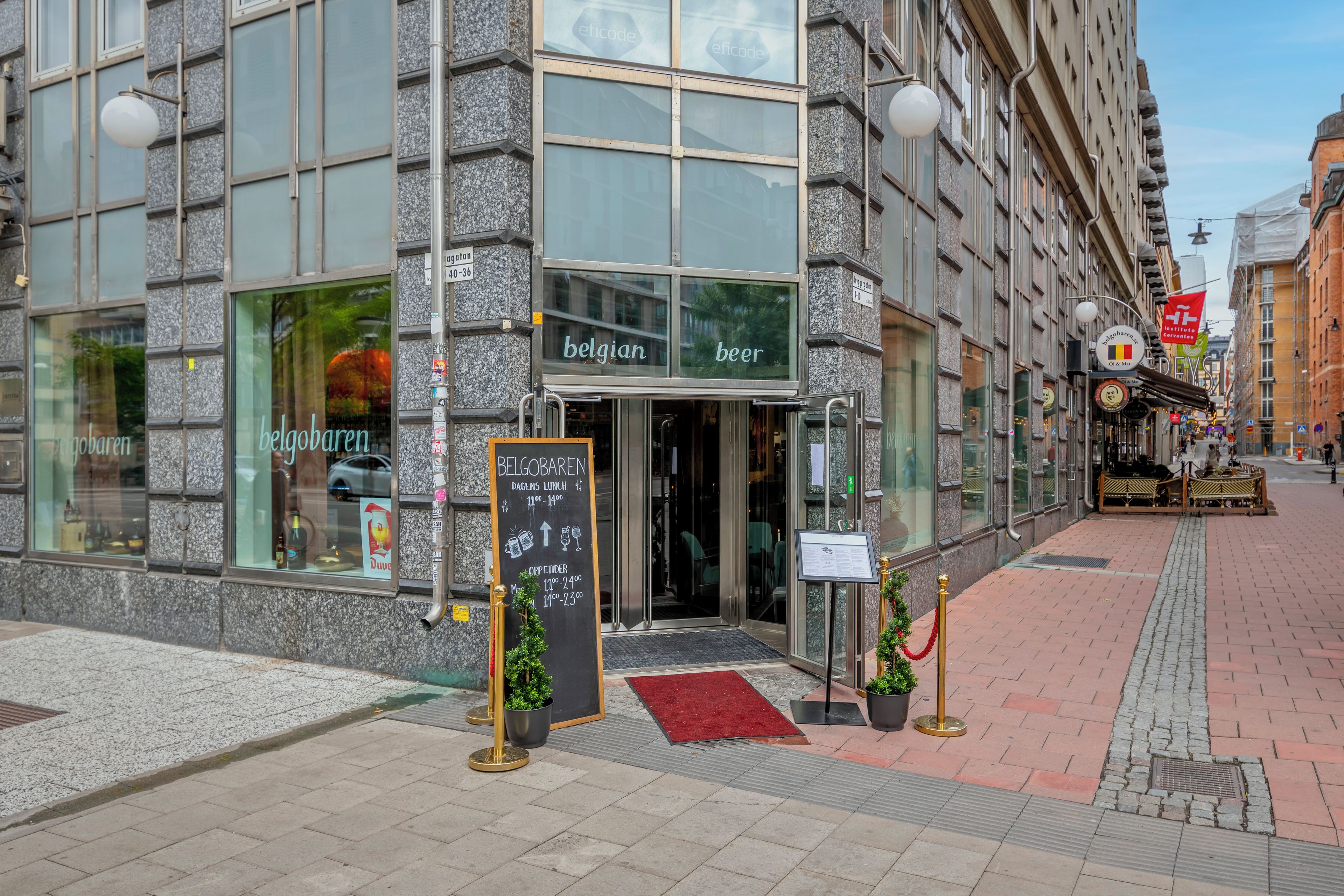 A building with a glass storefront labeled 'belgobaren' and a chalkboard sign indicating 'BELGOBAREN' with a red carpet entrance.