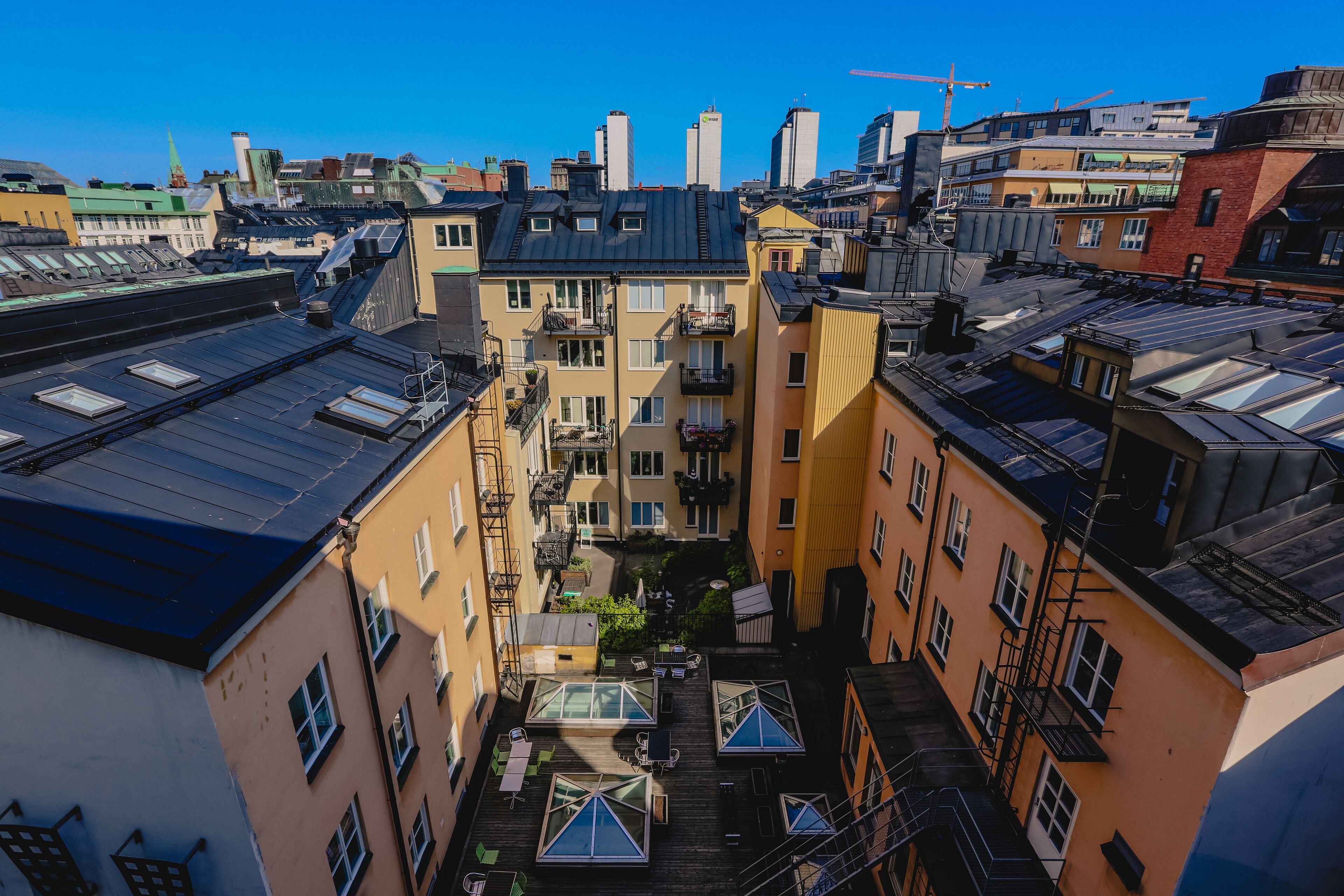 A narrow alleyway between buildings with a courtyard featuring a small garden and outdoor seating.