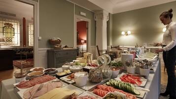 Ein reichhaltiges Buffet mit verschiedenen Speisen und einer Person, die bedient.