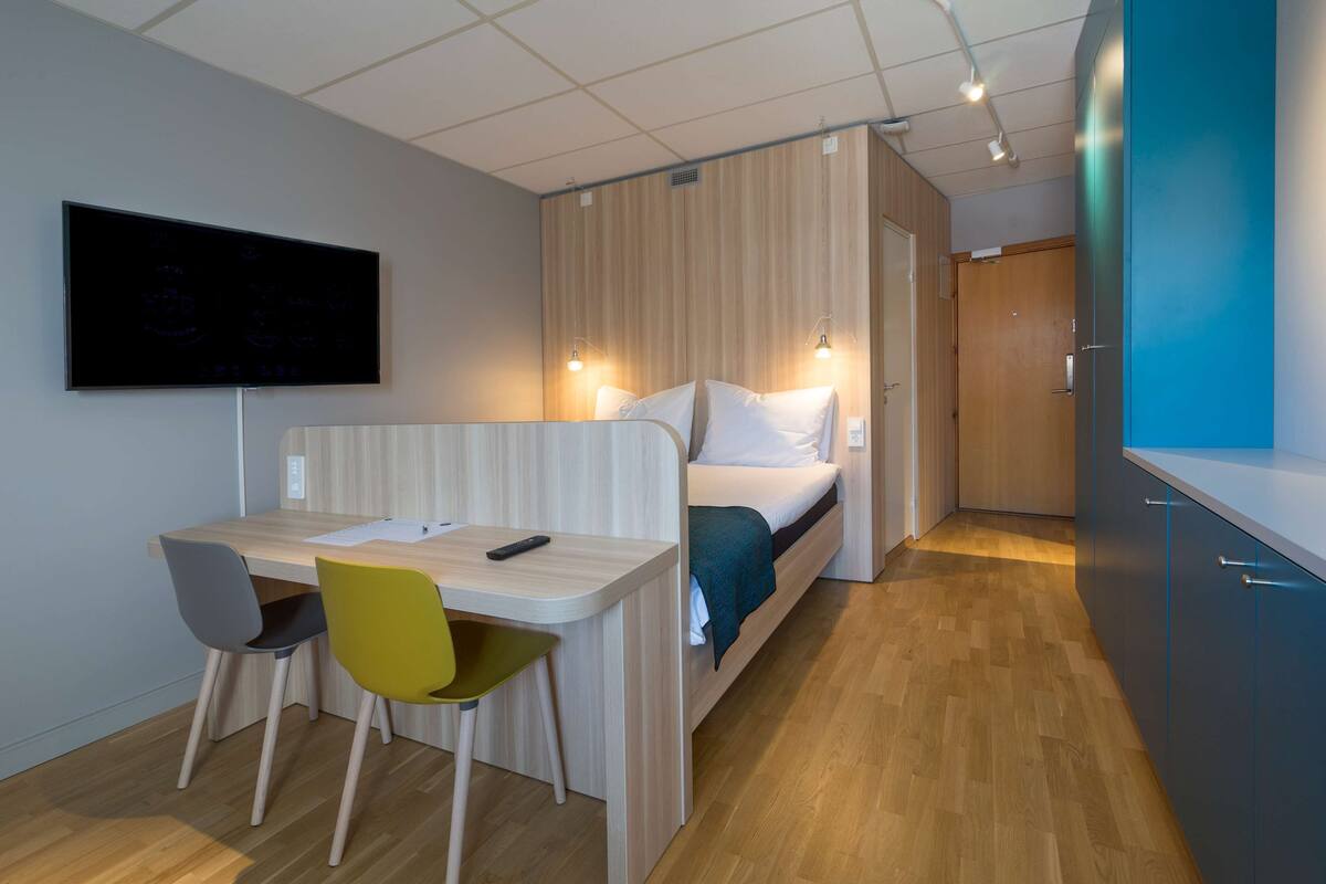 Ein modernes Zimmer mit einem Bett, einem Schreibtisch und zwei Stühlen.