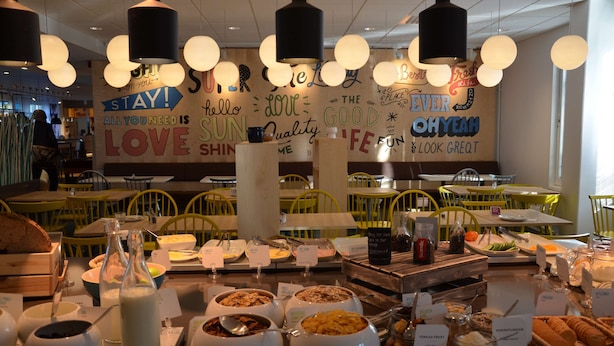 A breakfast buffet with various food items and a wall with motivational quotes. - Scandic Kista (Kista)
