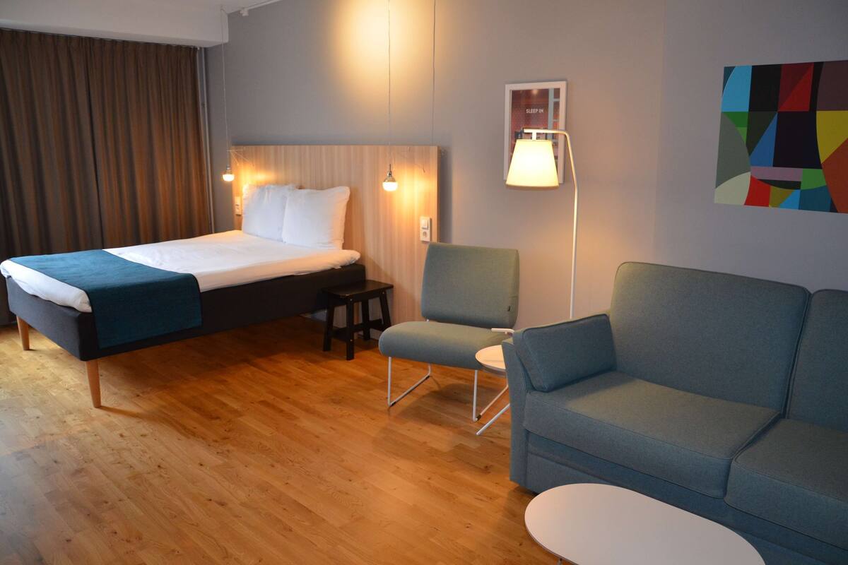 Ein Hotelzimmer mit einem Bett, einem Sofa, einem Sessel und einem kleinen Tisch.