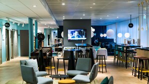 A modern lounge area with seating, a television, and a bar. - Scandic Kista (Kista)