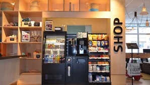 A shop with a coffee machine, shelves with snacks, and a sign that says "SHOP". - Scandic Kista (Kista)