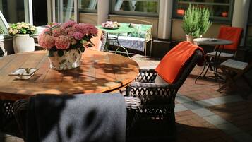 A cozy outdoor seating area with a round wooden table, wicker chairs, and a potted plant.