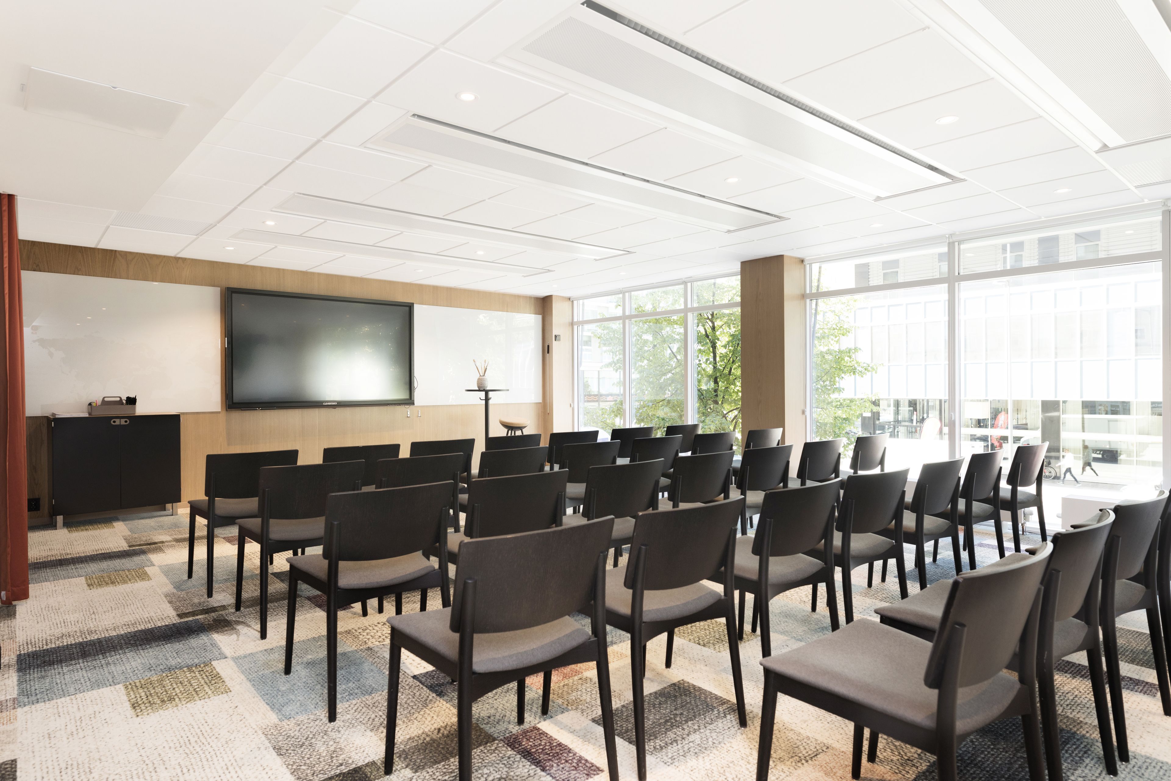 A conference room with rows of chairs, a large screen, and a projector.