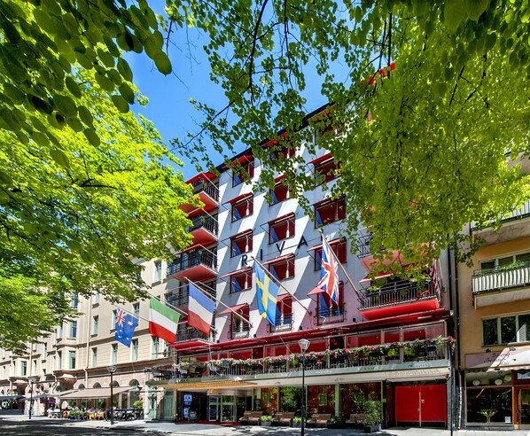 A multi-story hotel with balconies, flags, and outdoor seating areas.