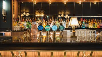 Una zona de bar con múltiples grifos de cerveza, una variedad de botellas y una pila de vasos.