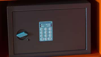 A black safe with a keypad and a blue keyhole, placed on an orange shelf.