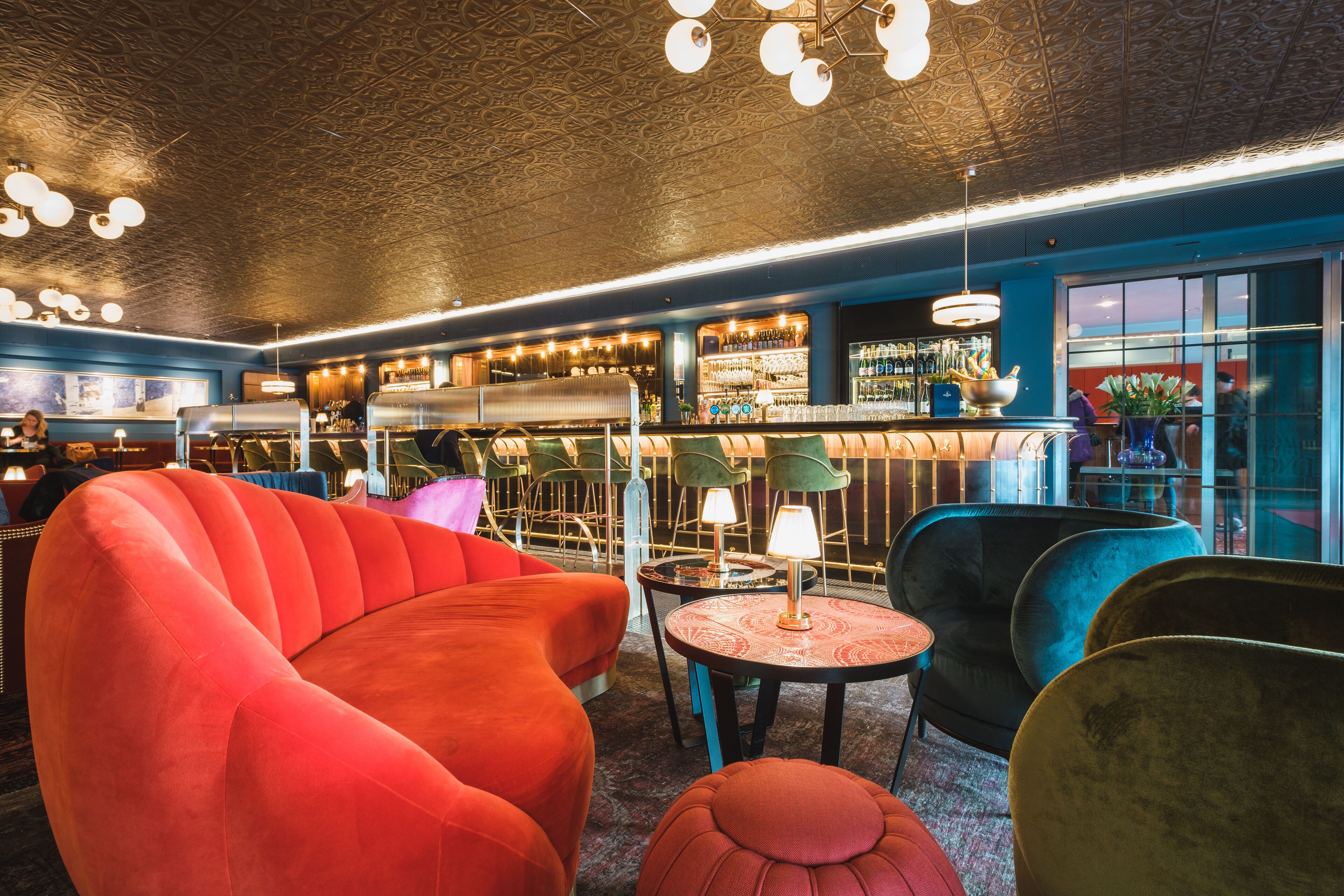A bar area with seating, a bar counter, and a variety of bottles and glasses.