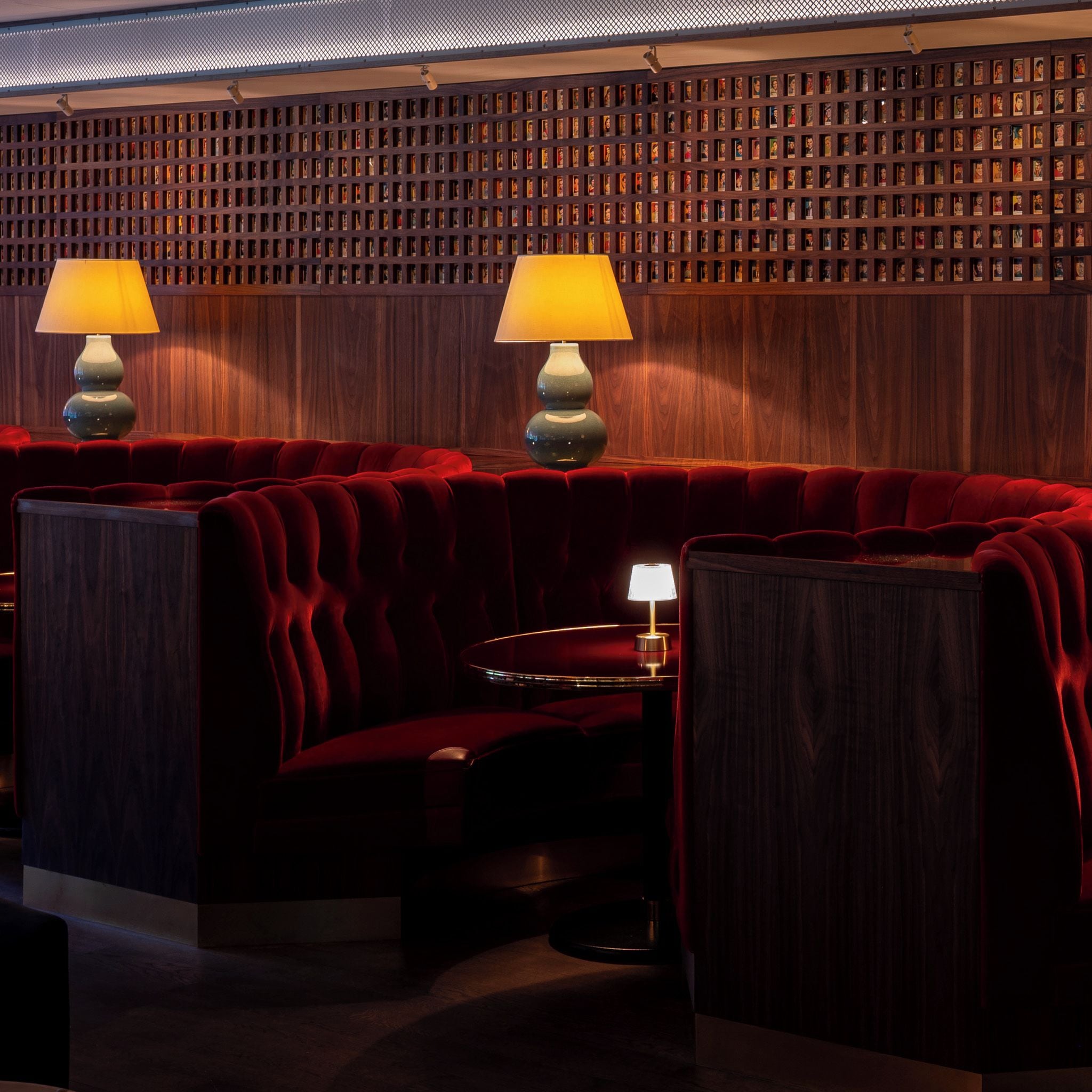 A dimly lit room with a red velvet sofa and two lamps.