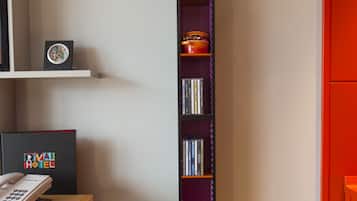 Ein Bücherregal mit verschiedenen Gegenständen, darunter Bücher, DVDs und einem gerahmten Bild.
