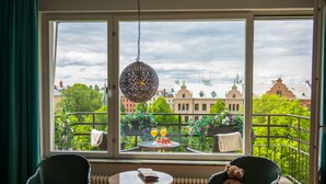 A room with a view of a balcony, a round table with a book, a chair, and a teddy bear. - Hotel Rival (Stockholm)
