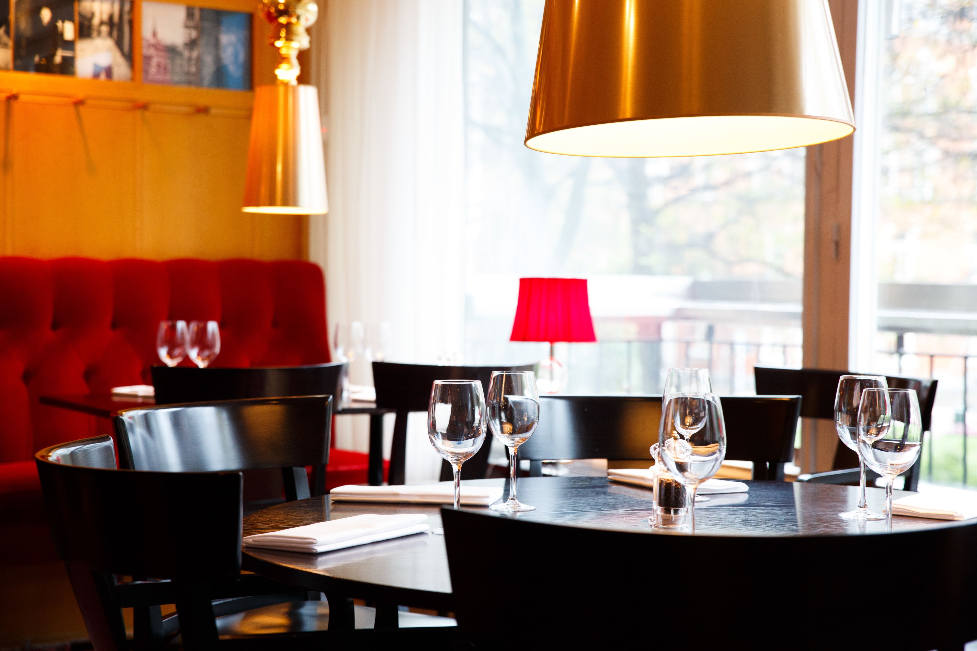 Un interior de restaurante con una mesa redonda dispuesta para comer, asientos tapizados en rojo e iluminación colgante.