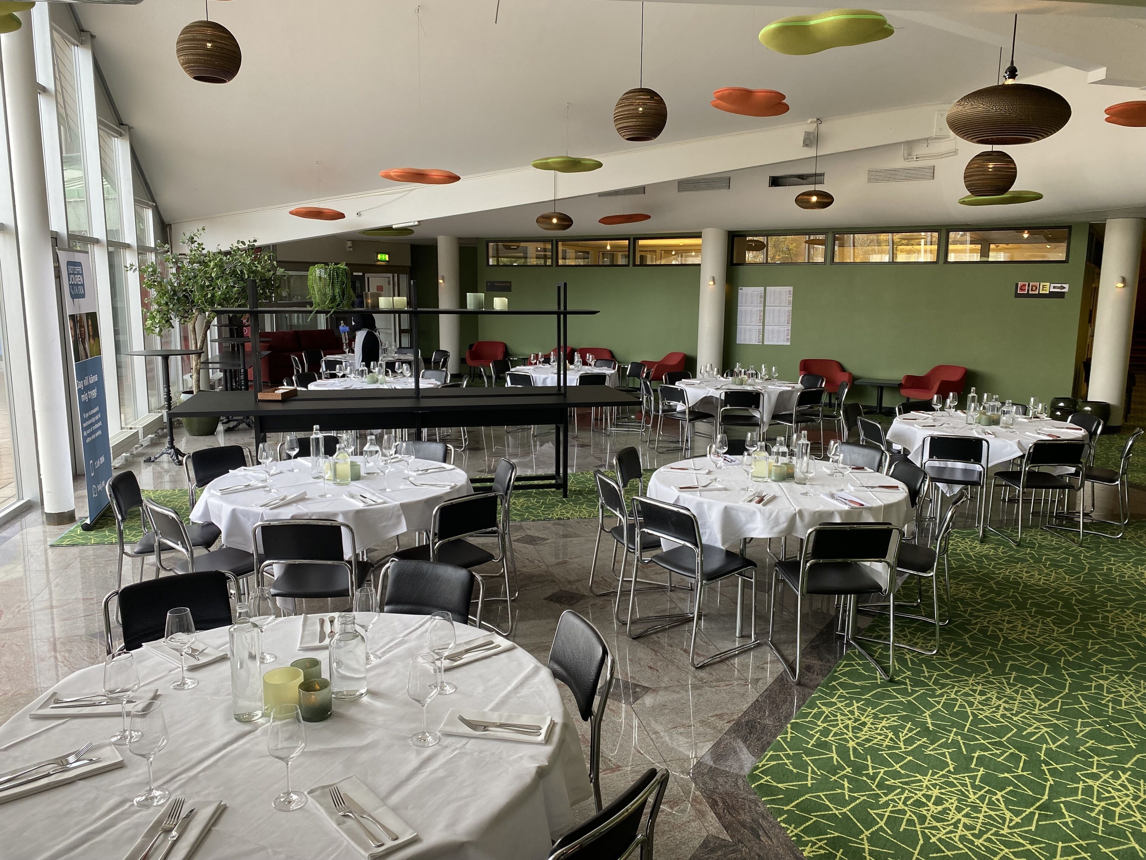 A spacious dining area with round tables set for dining, surrounded by chairs.