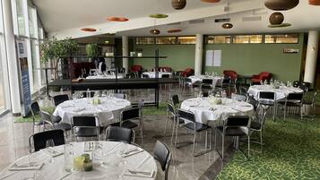 A spacious dining area with round tables set for dining, surrounded by chairs.