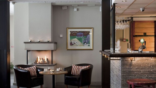 Un área de bar con chimenea, dos sillones y una mesa redonda.