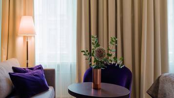 Ein modernes Hotelzimmer mit einer Couch, einem runden Tisch, einer Lampe und einer Vase mit Blumen.