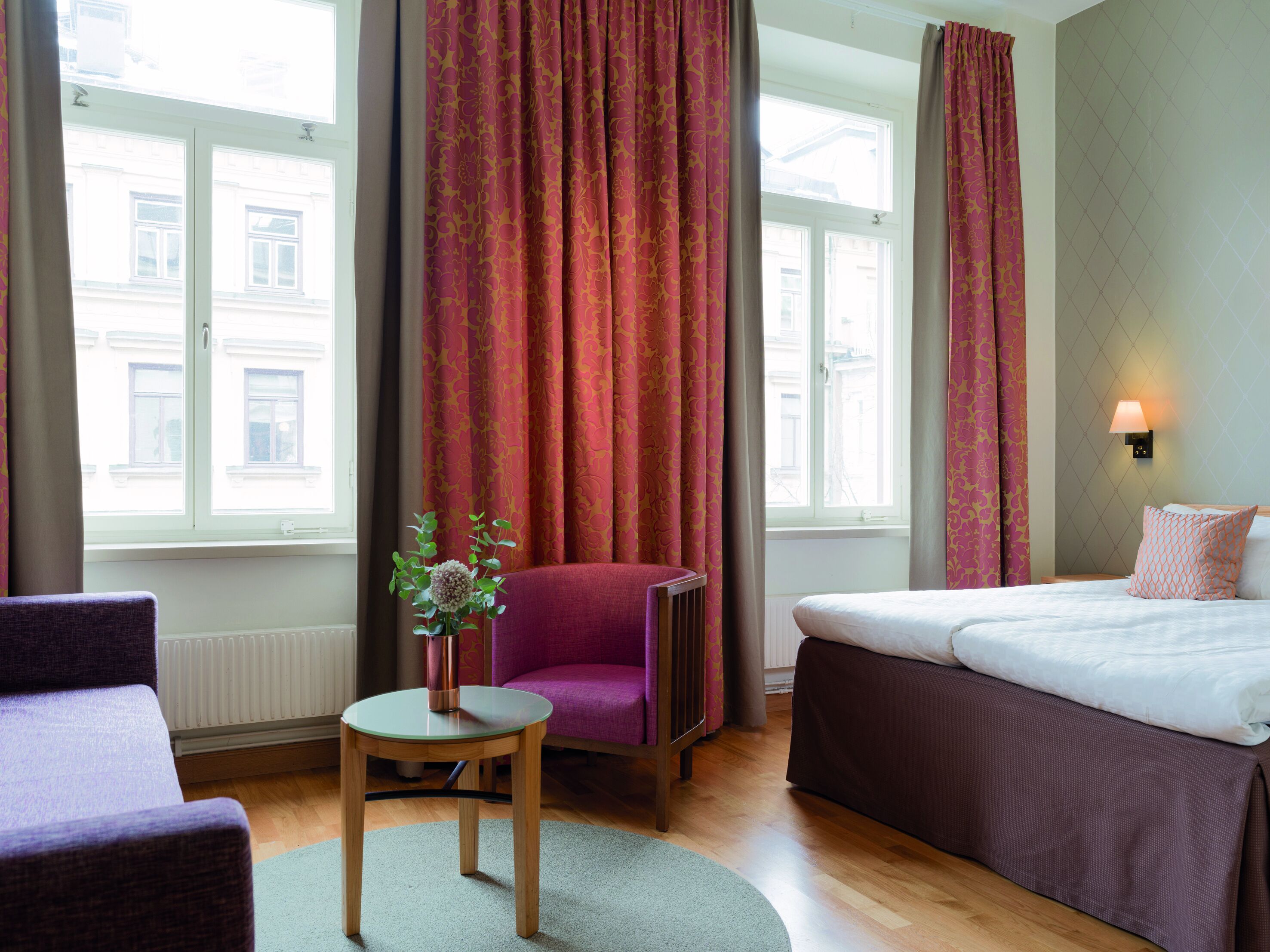 Ein Hotelzimmer mit Bett, Stuhl, Tisch und einem fensterbepflanzten Fenster.