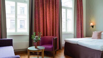 Ein Hotelzimmer mit Bett, Stuhl, Tisch und einem fensterbepflanzten Fenster.