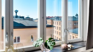 Näkymä ikkunasta, josta avautuu kaupunkimaisema, jossa on näkyvissä rakennuksia ja torni.
